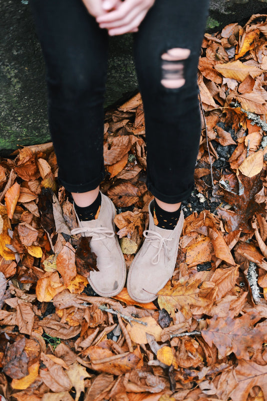 a man and woman wearing boots in the forest during fall