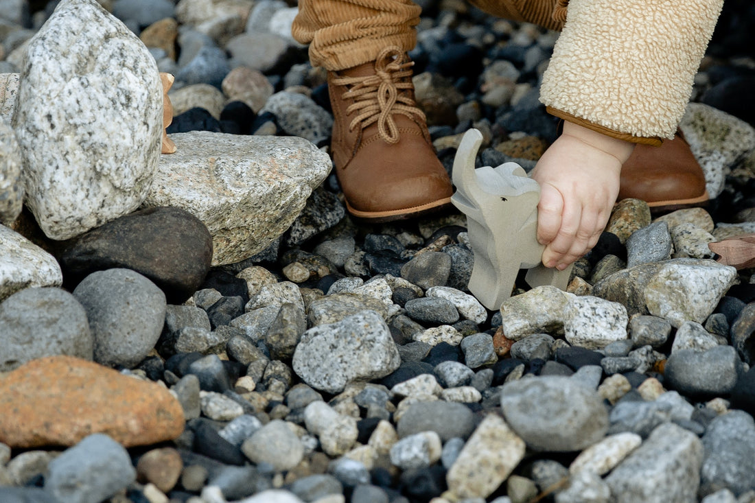 A child wearing new shoes and playing with a toy elephant